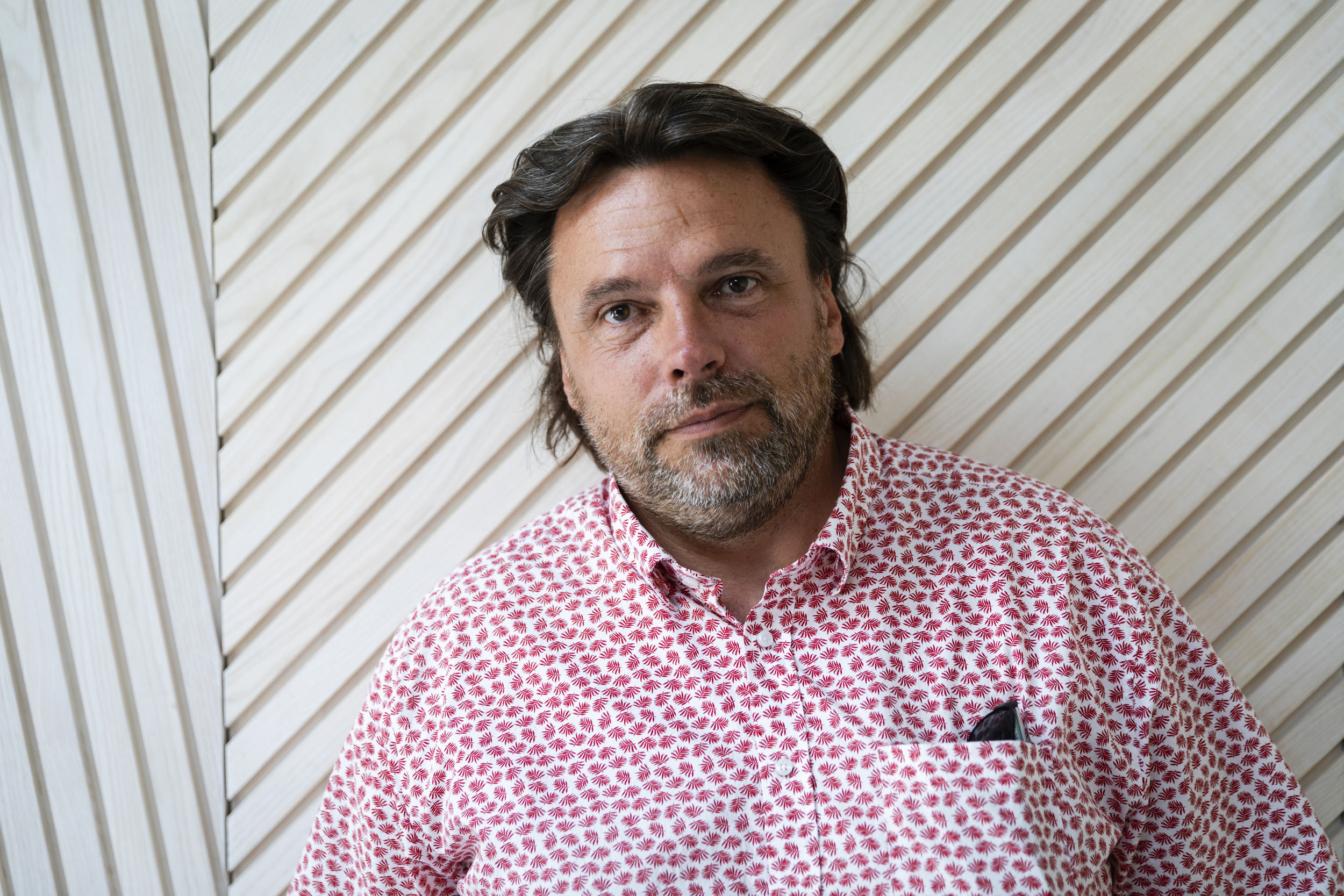 Portrait en lumière du jour de l'architecte Thierry Bonne cadré en plan buste sur fond clair, il regarde dans l'objectif