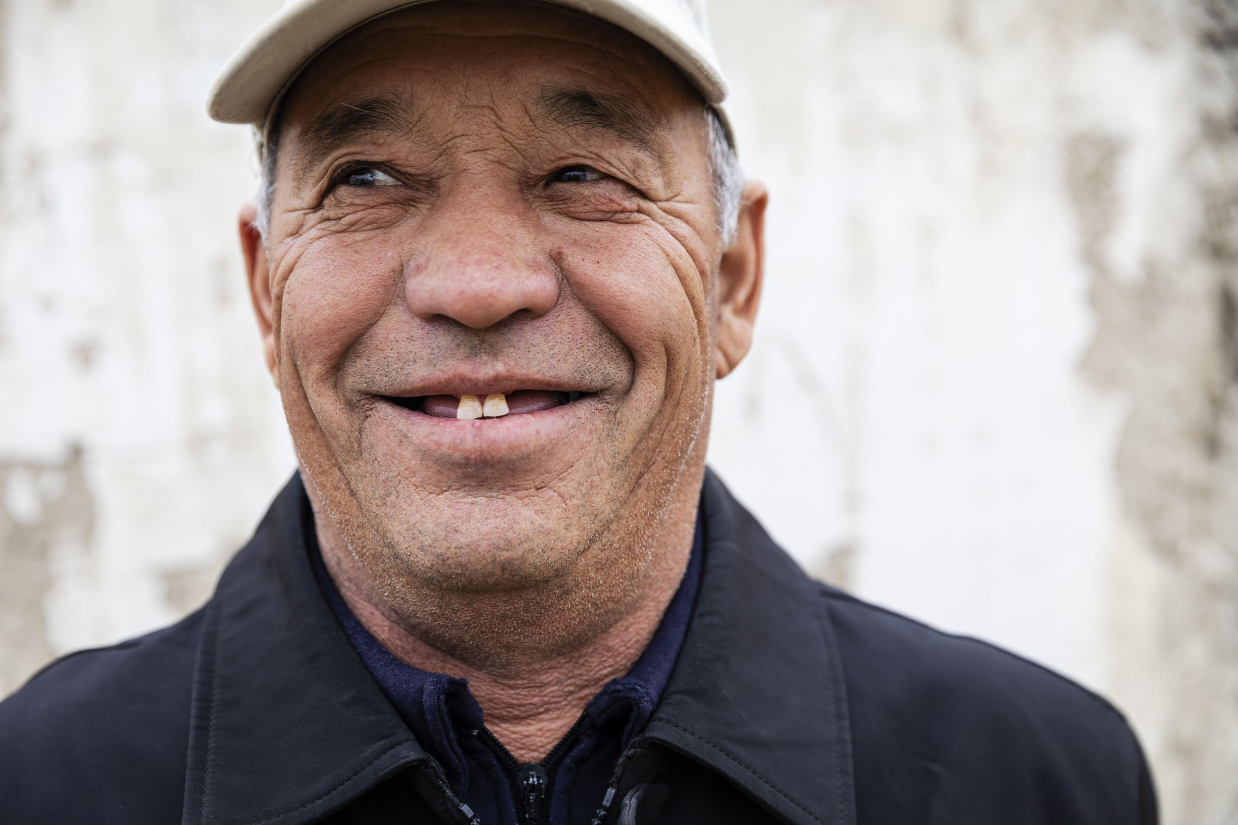 Portrait en gros plan d'un homme Ouzbek édenté et souriant portant une casquette dans les rues de Moynaq en Ouzbékistan