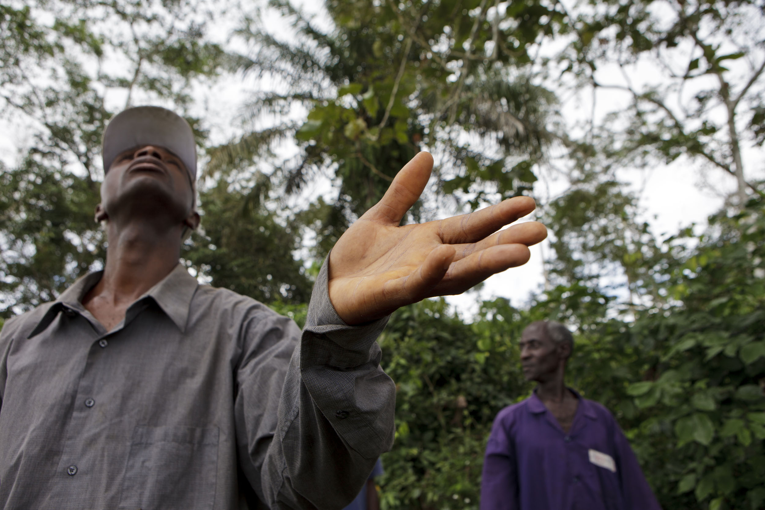 En Côte d’ivoire, en homme coiffé d'une casquette regarde et tend la main vers le ciel dans l'espoir de l'arrivée de la pluie, la photo est en contreplongée