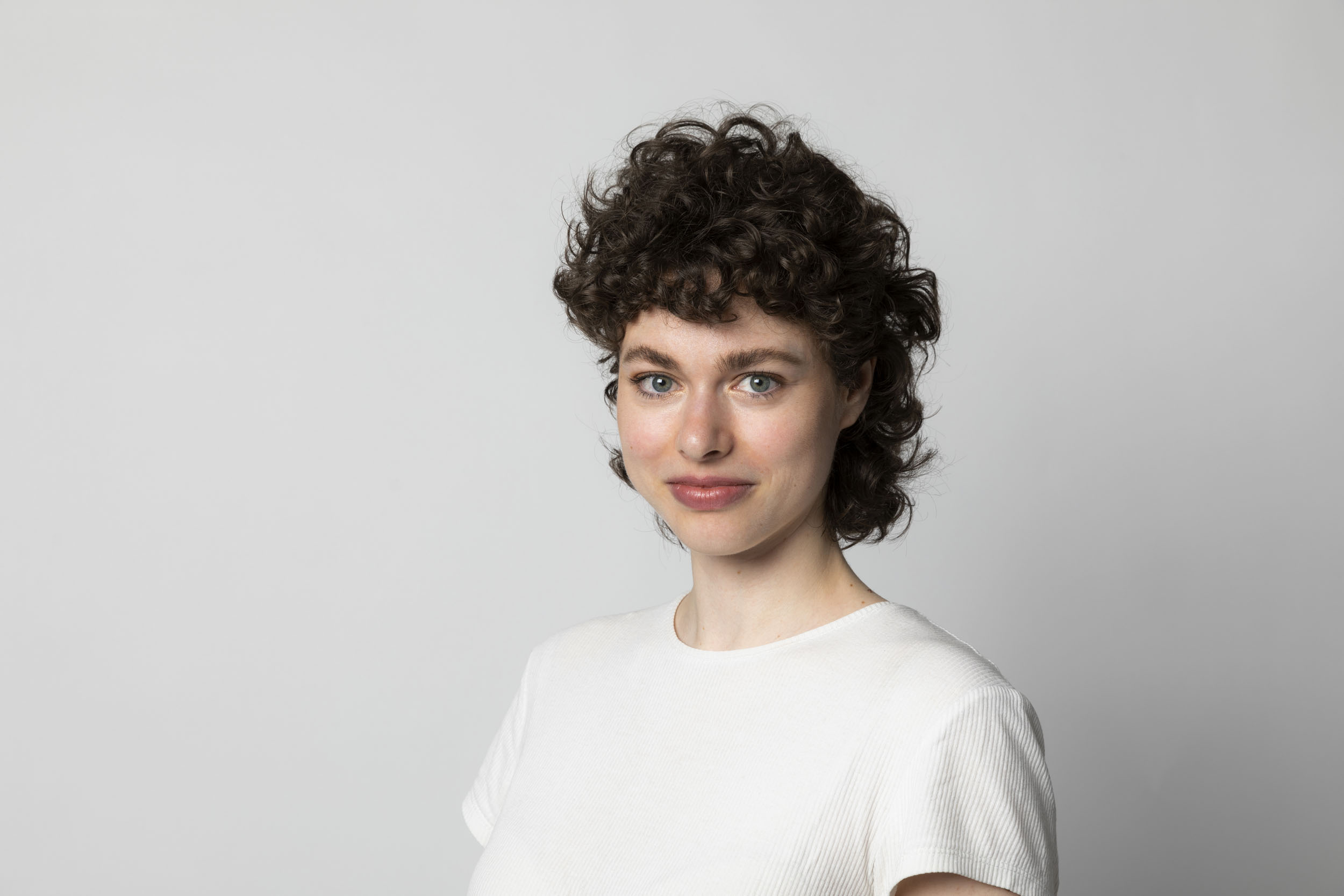 Portrait de profil réseaux sociaux en couleur d'une jeune femme brune souriante sur fond gris clair
