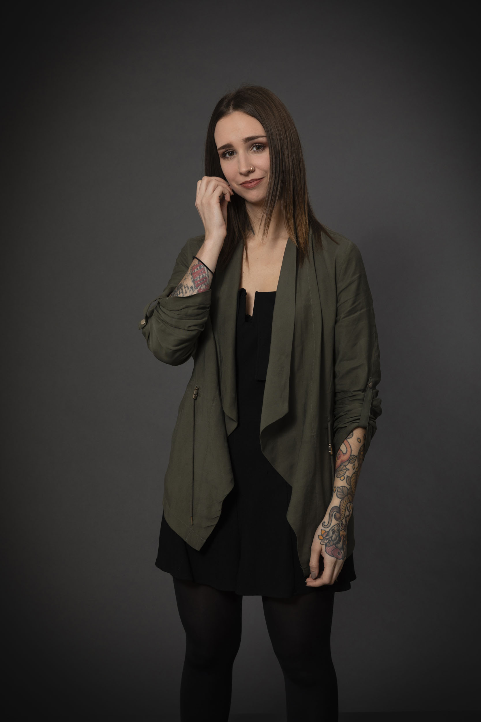 Portrait de profil réseau social en couleur d'une jeune femme aux bras tatoués sur fond gris foncé en studio