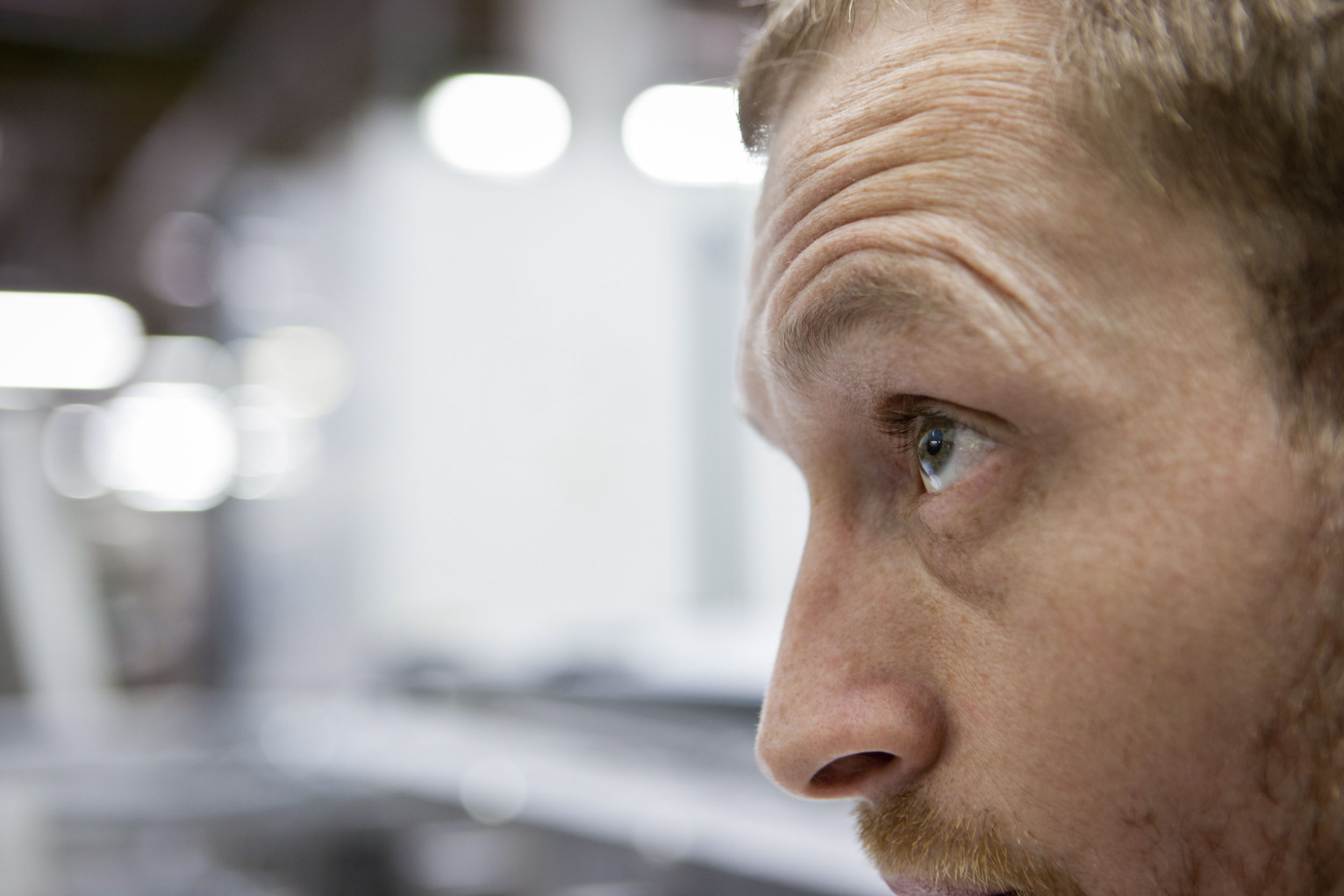 Portrait en très gros plan d'un homme au travail dans un atelier de fabrication de cahiers. Reportage photographique commandé par le Groupe Hamelin à Caen.