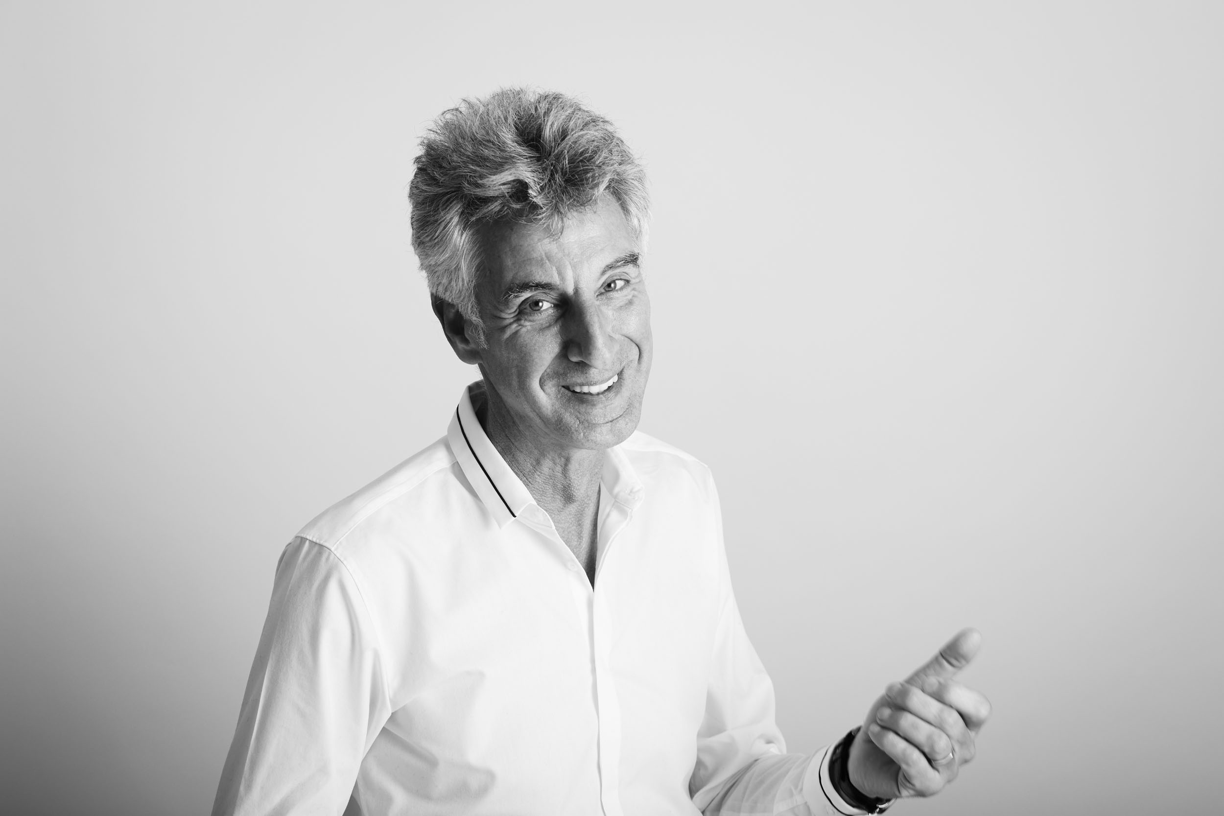 Portrait photographique de profil réseau social en noir & blanc d'un homme souriant sur fond gris clair réalisée par un photographe portraitiste professionnel