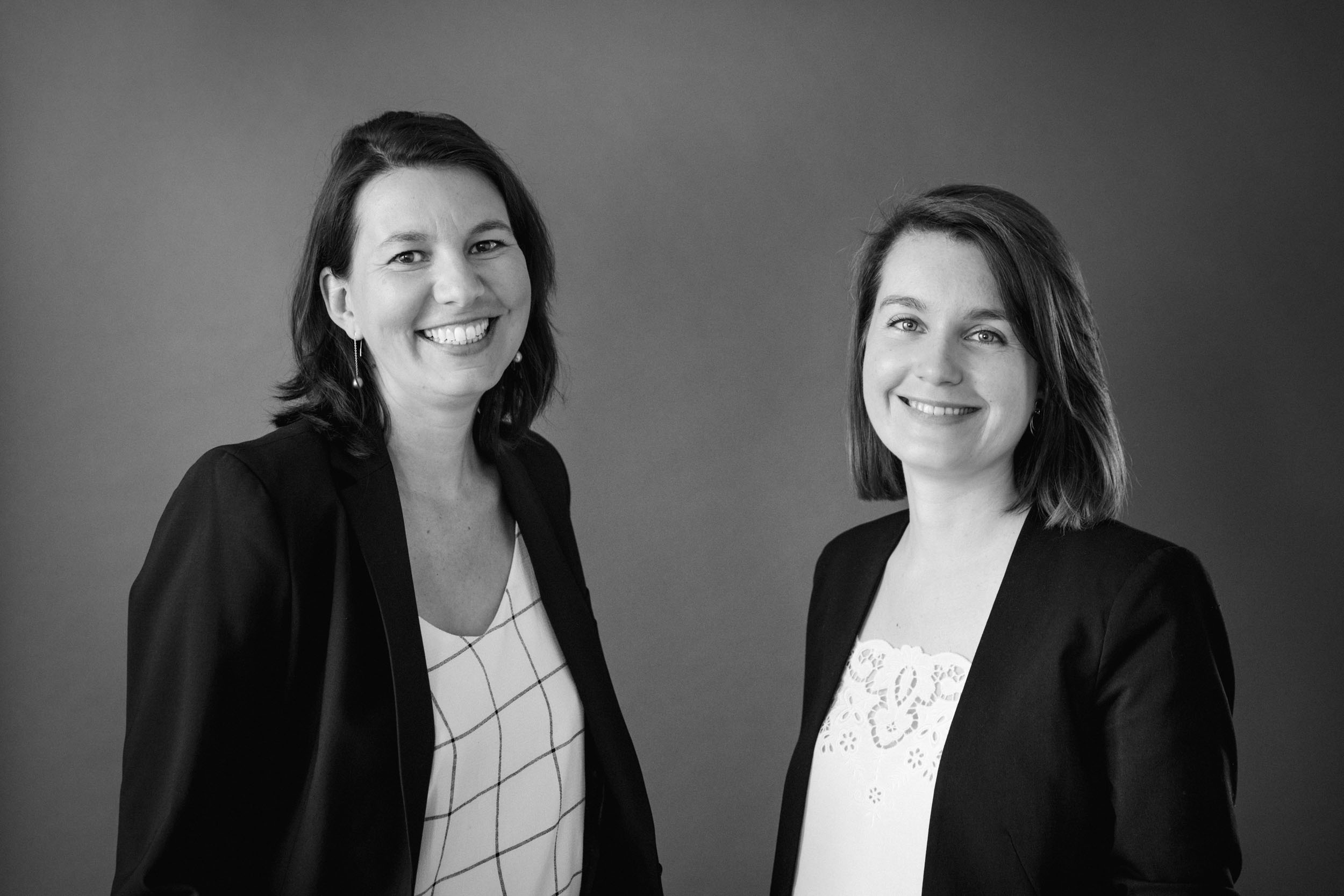 Portrait réseaux sociaux noir et blanc en duo de 2 femmes avocates côtes à côtes en plan buste sur fond gris