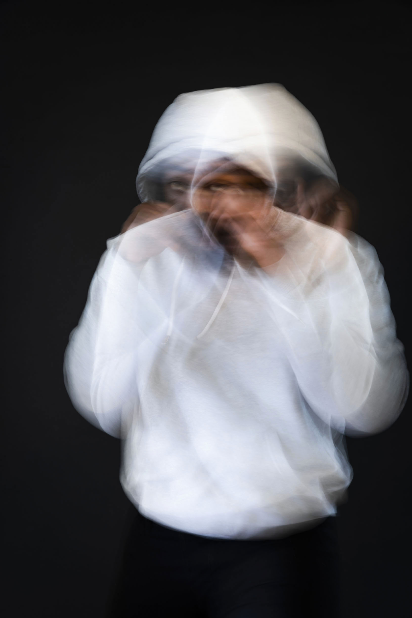 Portrait artistique flou sur fond noir d'un boxeur à l'entraînement vêtu d'un sweat-shirt à capuche. Cadrage en plan américain