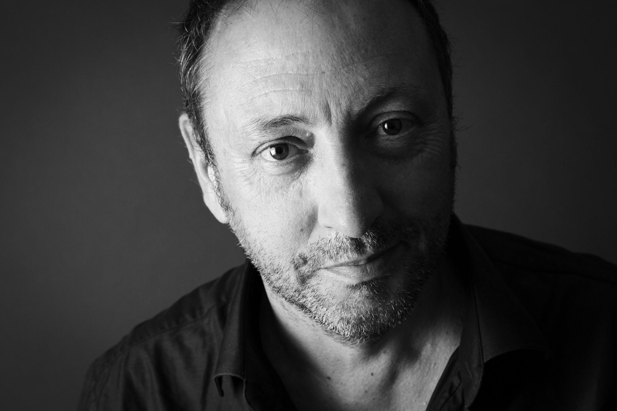 Portrait artistique en noir et blanc en gros plan du paysagiste Thierry Jourd'heuil. Portrait réalisé en studio sur fond gris foncé
