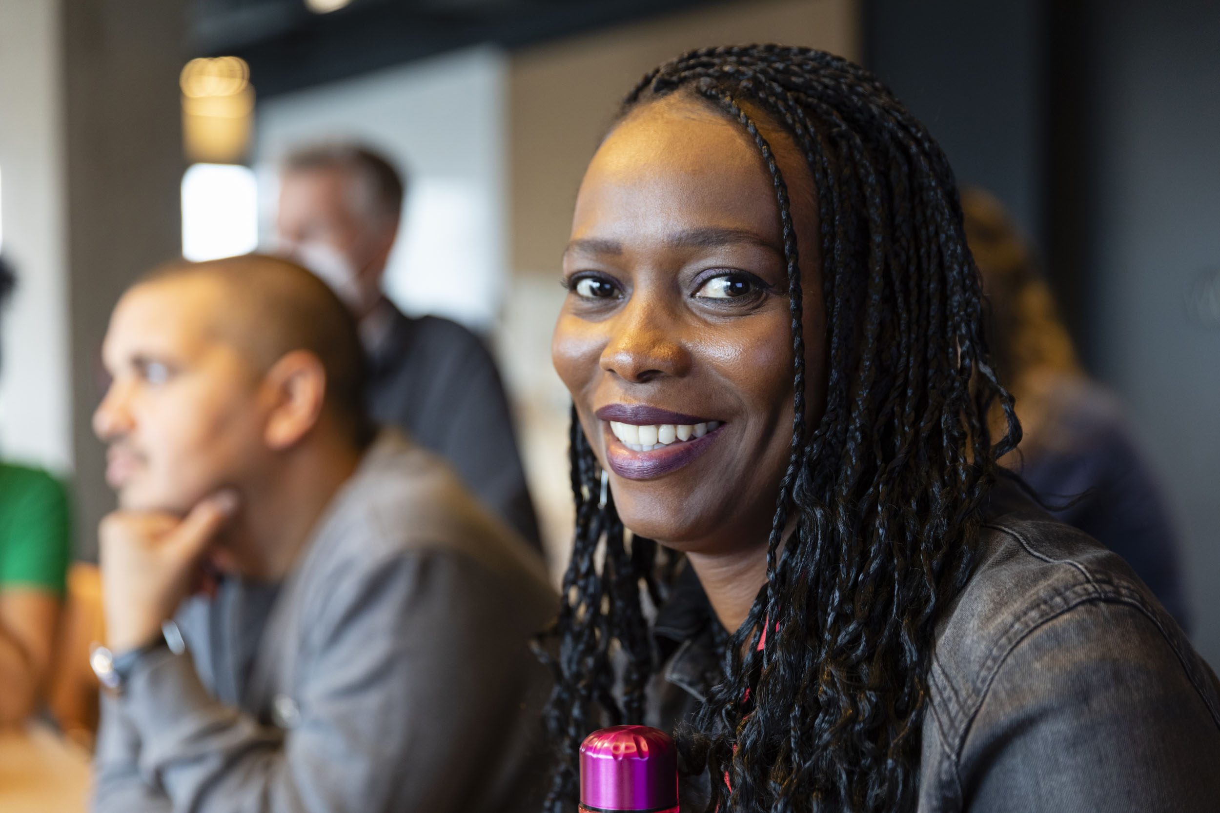 Portrait d'une collaboratrice portant des tresses pendant une réunion dans l'entreprise. Elle sourit et regarde dans l'objectif