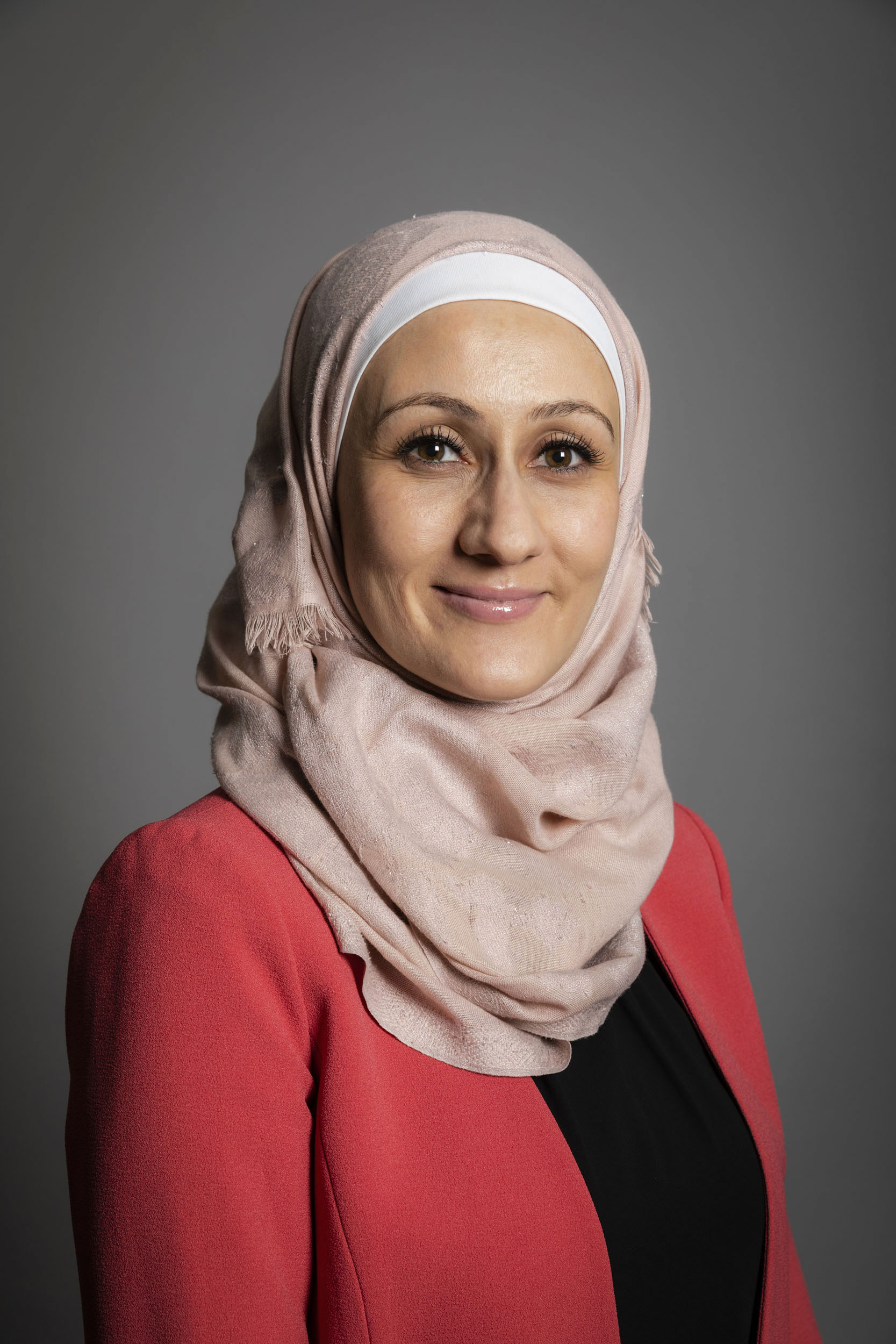 Photo de portrait d'une femme souriante portant le voile réalisé en studio mobile sur fond gris. Portrait corporate commandé par la société Abbvie.