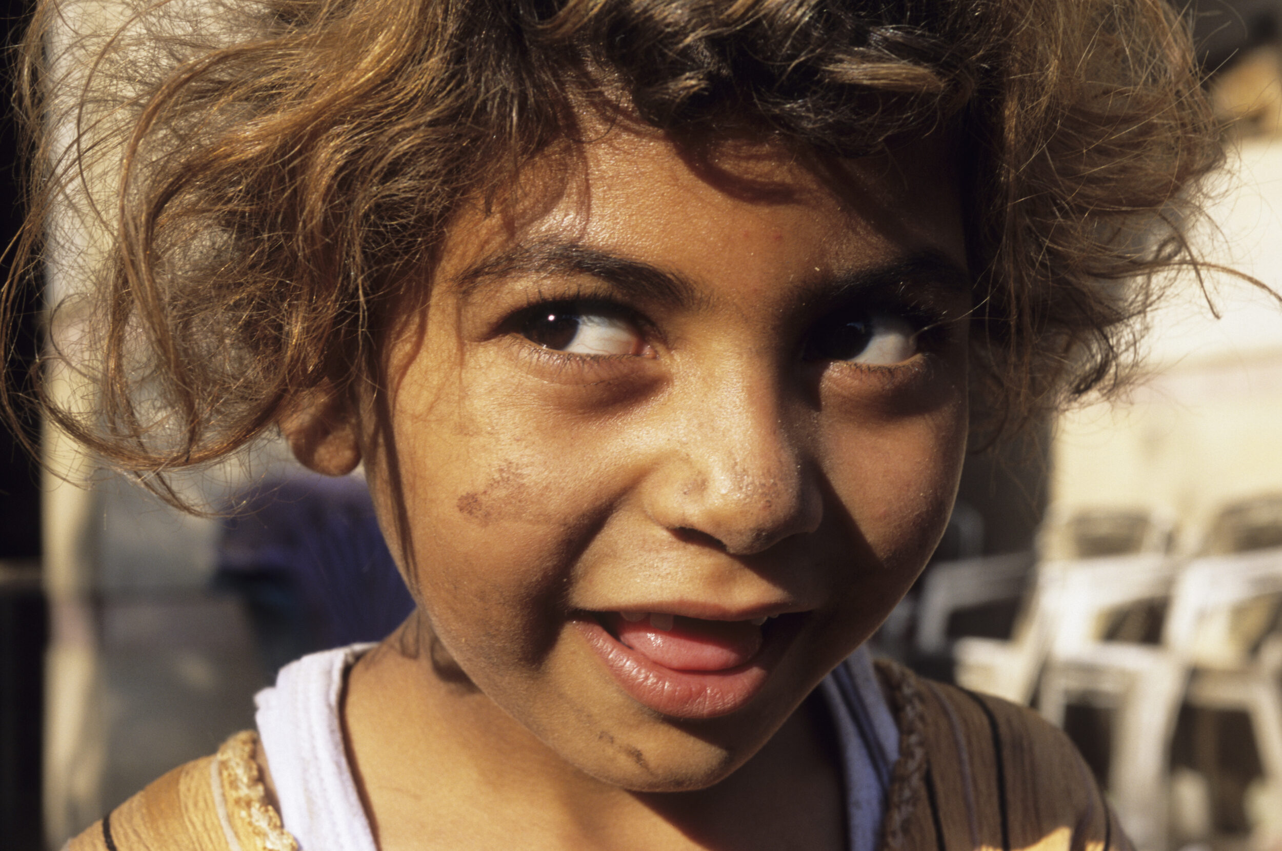 Portrait en gros plan d'une enfant chiffonnière éclairée par une lumière naturelle chaude dans dans le quartier du Mokattam au Caire en Égypte