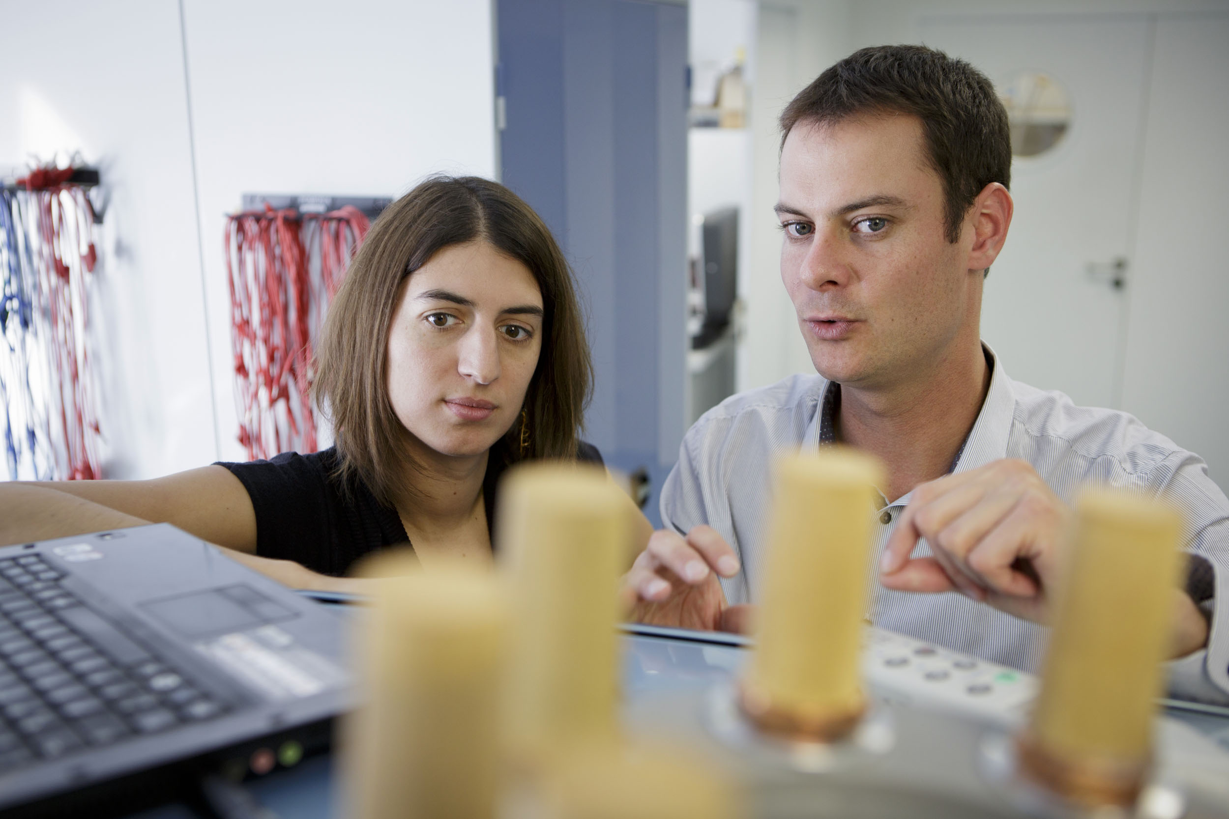 Portraits d'une équipe, 1 femme à gauche et 1 homme à droite, dans un laboratoire de recherche du CEA List. Il réalise des tests sur un véhicule électrique