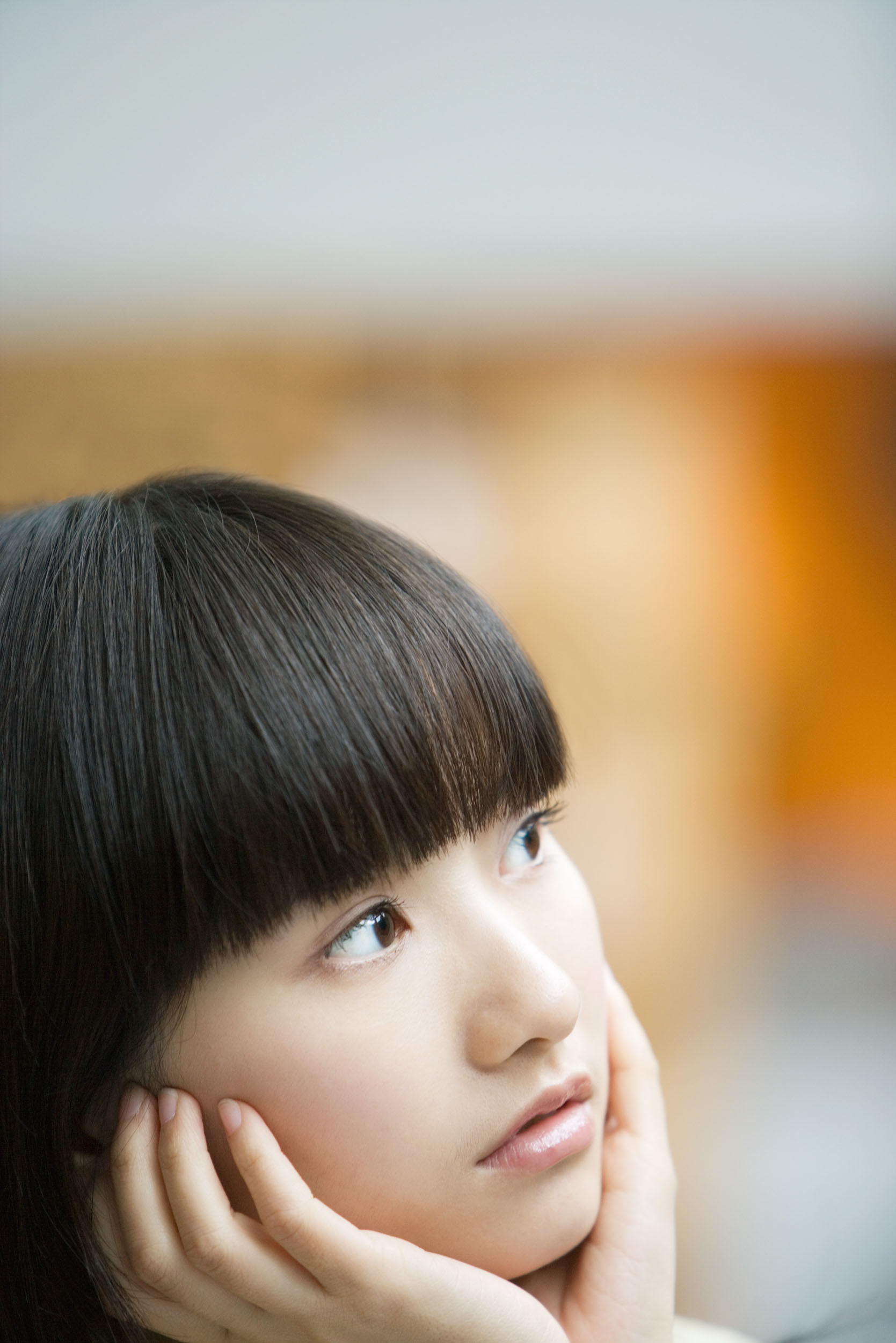 Portrait graphique de profil d'une femme asiatique à la lumière du jour, elle tient le bas de son visage dans ses mains