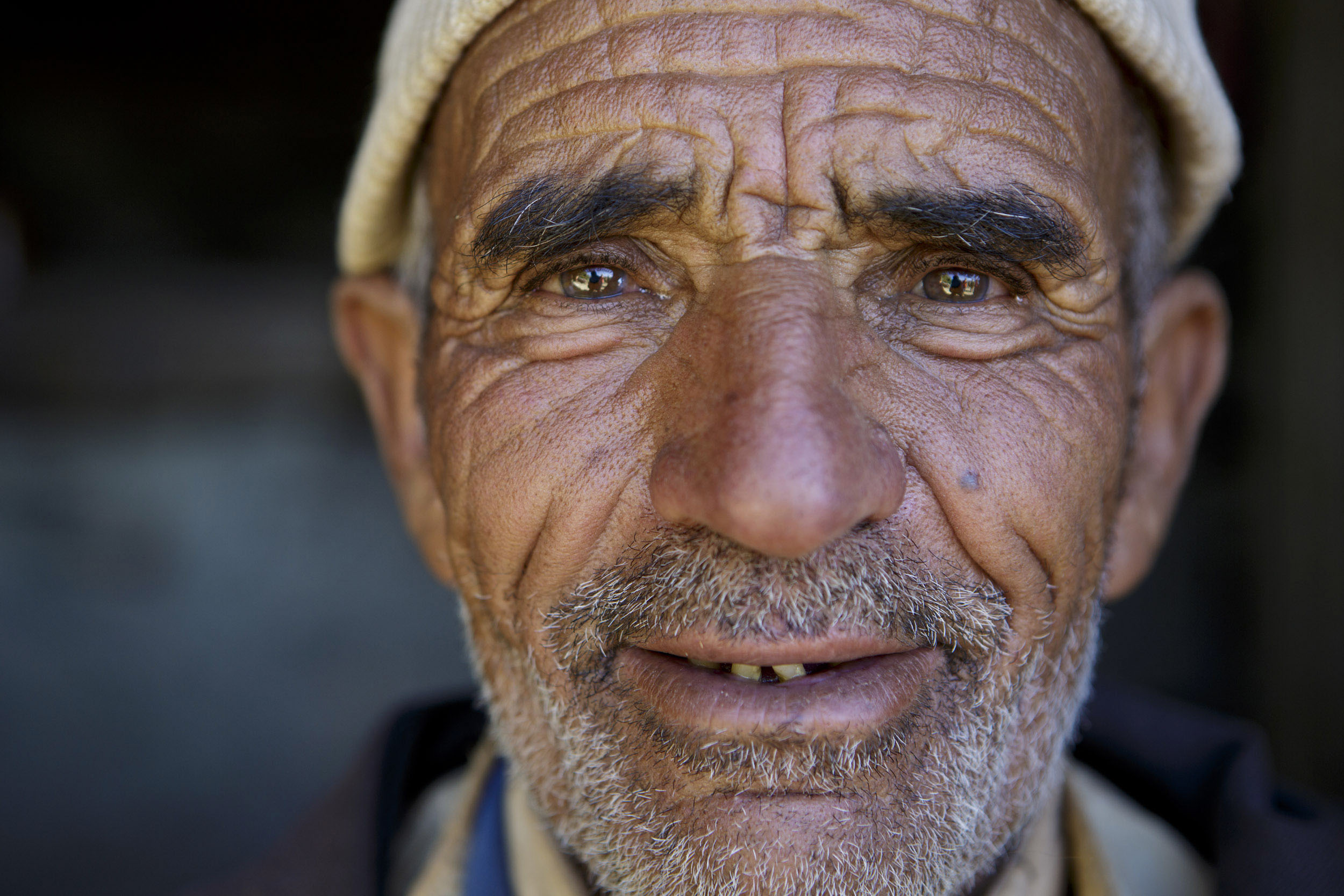 Portrait frontale en gros plan d'un berger berbère ridée et édenté portant un bonnet blanc sur la tête dans la vallée d'Anergie au Maroc. Il regarde dans l'objectif.