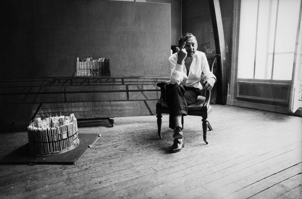 Portrait en noir et blanc et en plan large de l'artiste peintre et sculpteur franco-roumain Horia Damian dans son atelier de Montparnasse à Paris