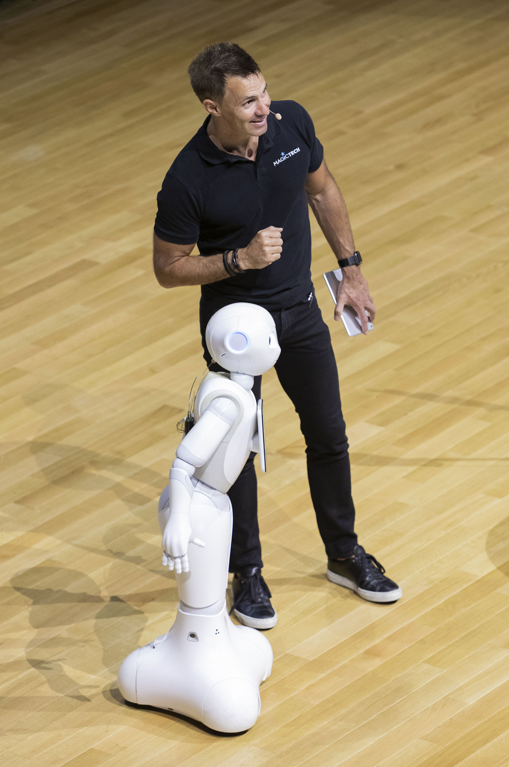 Portrait d'un intervenant sur scène avec le robot Pepper lors d'une convention d'entreprise, photo réalisée en plongé