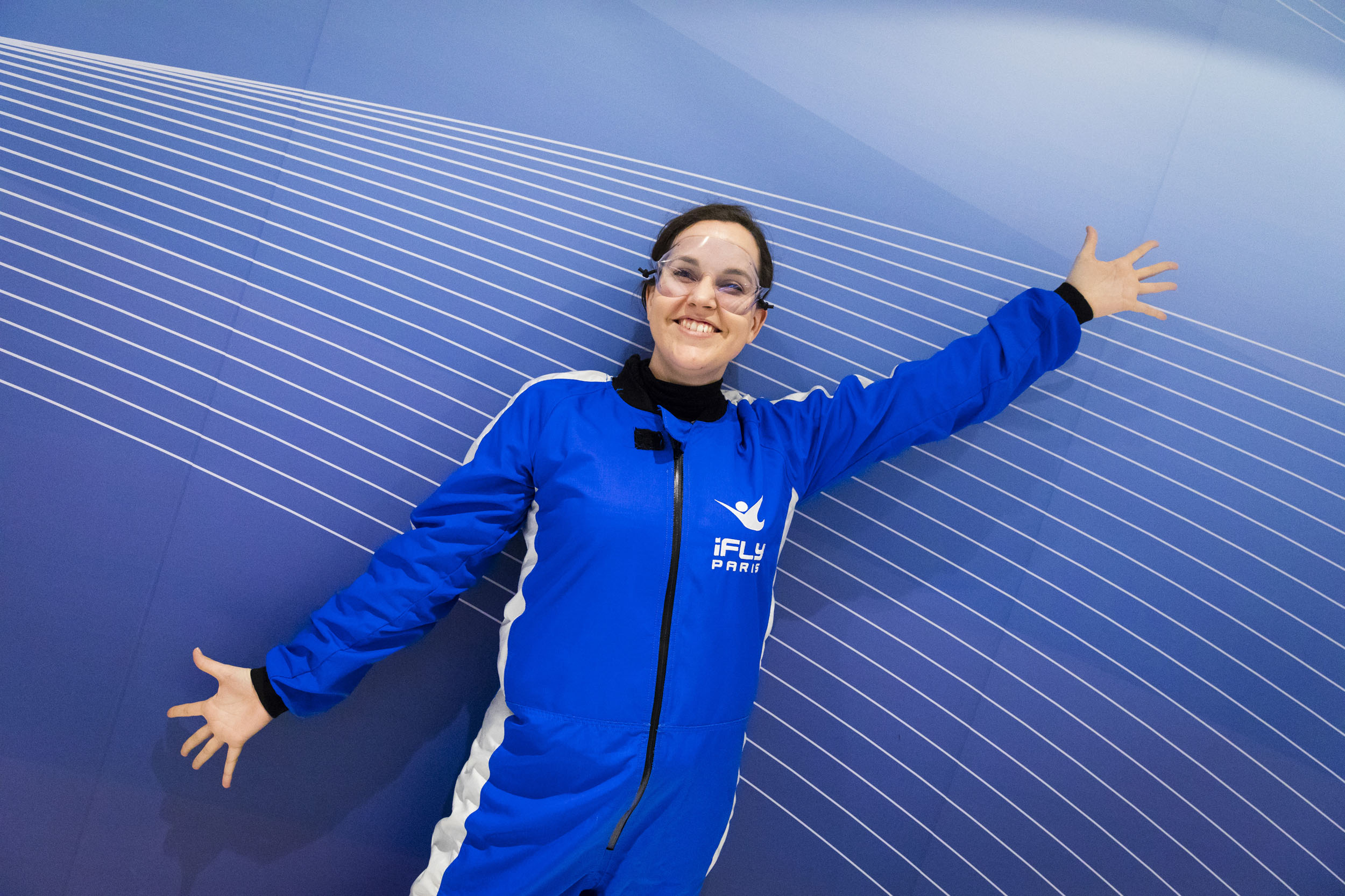 Portrait graphique d'une jeune femme souriante en combinaison bleu sur fond bleu participante à un team building sportif d'une entreprise