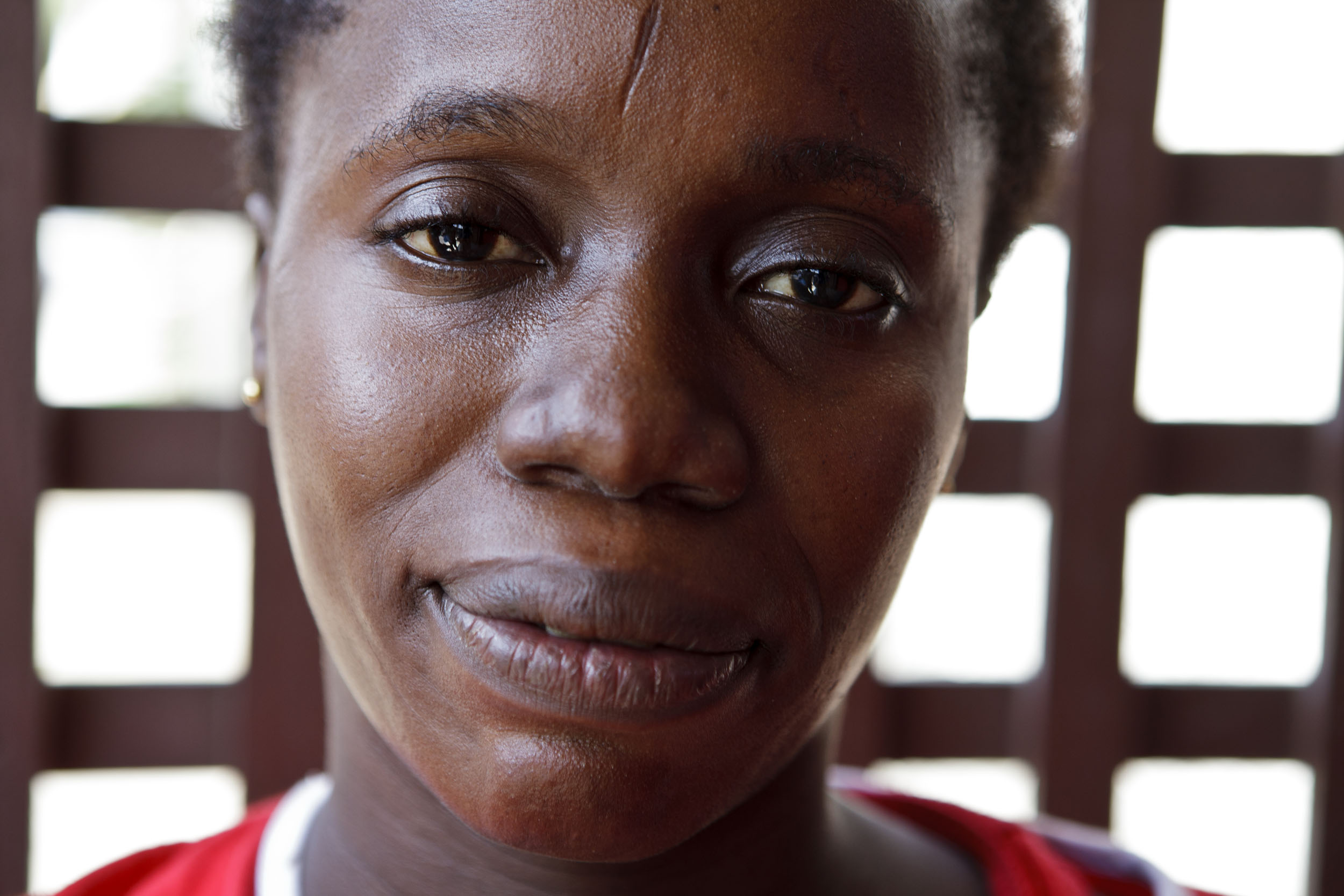 Portraits en gros plan d'une femme vendeuse de café en Côte d'Ivoire. Elle porte une scarification sur le front et regarde dans l'objectif