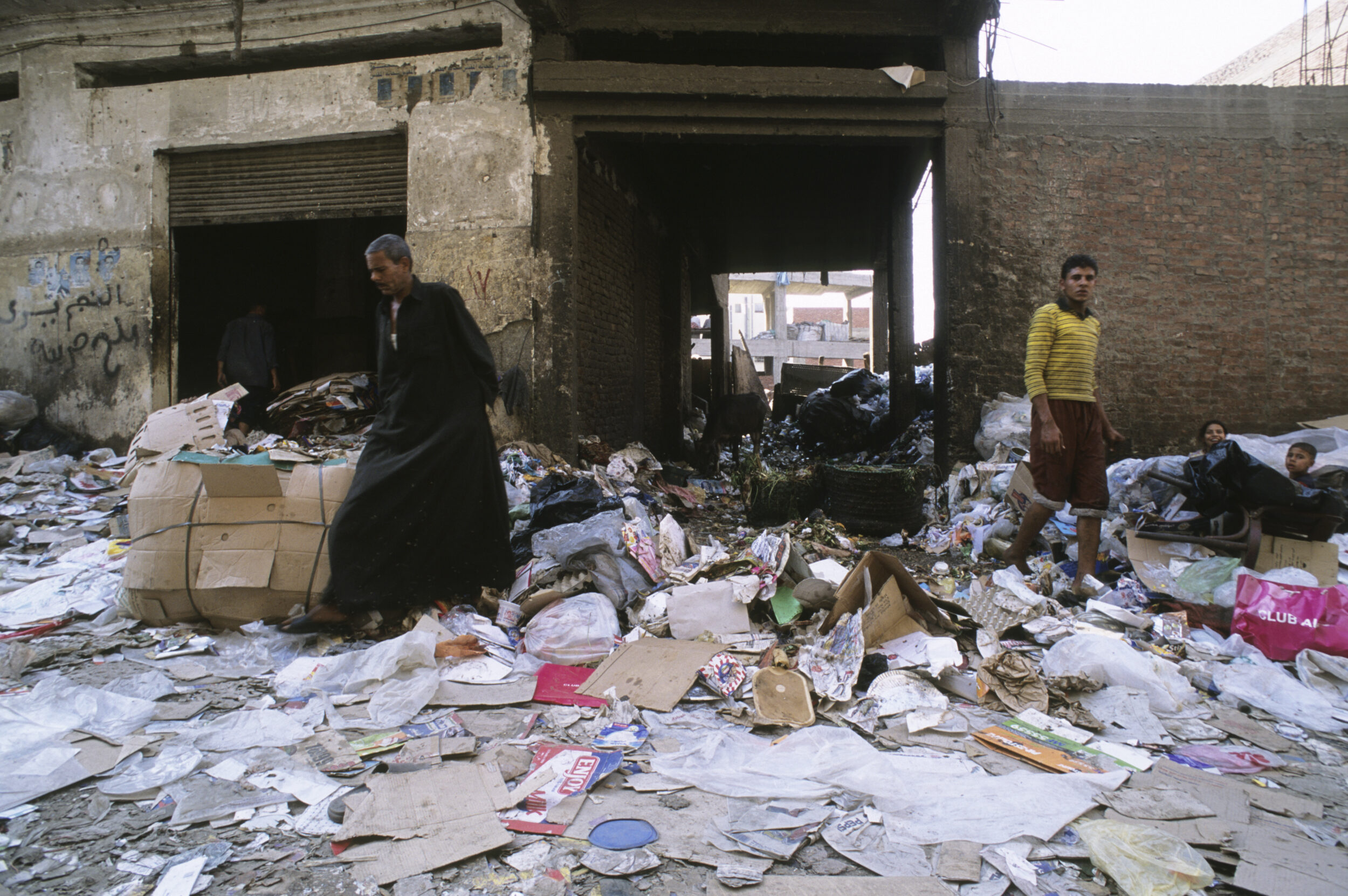 Devant une maison du quartier du Mokattam au Caire, la rue est jonchée d'ordures, cartons, papiers et plastique. 4 chiffonniers sont présents.