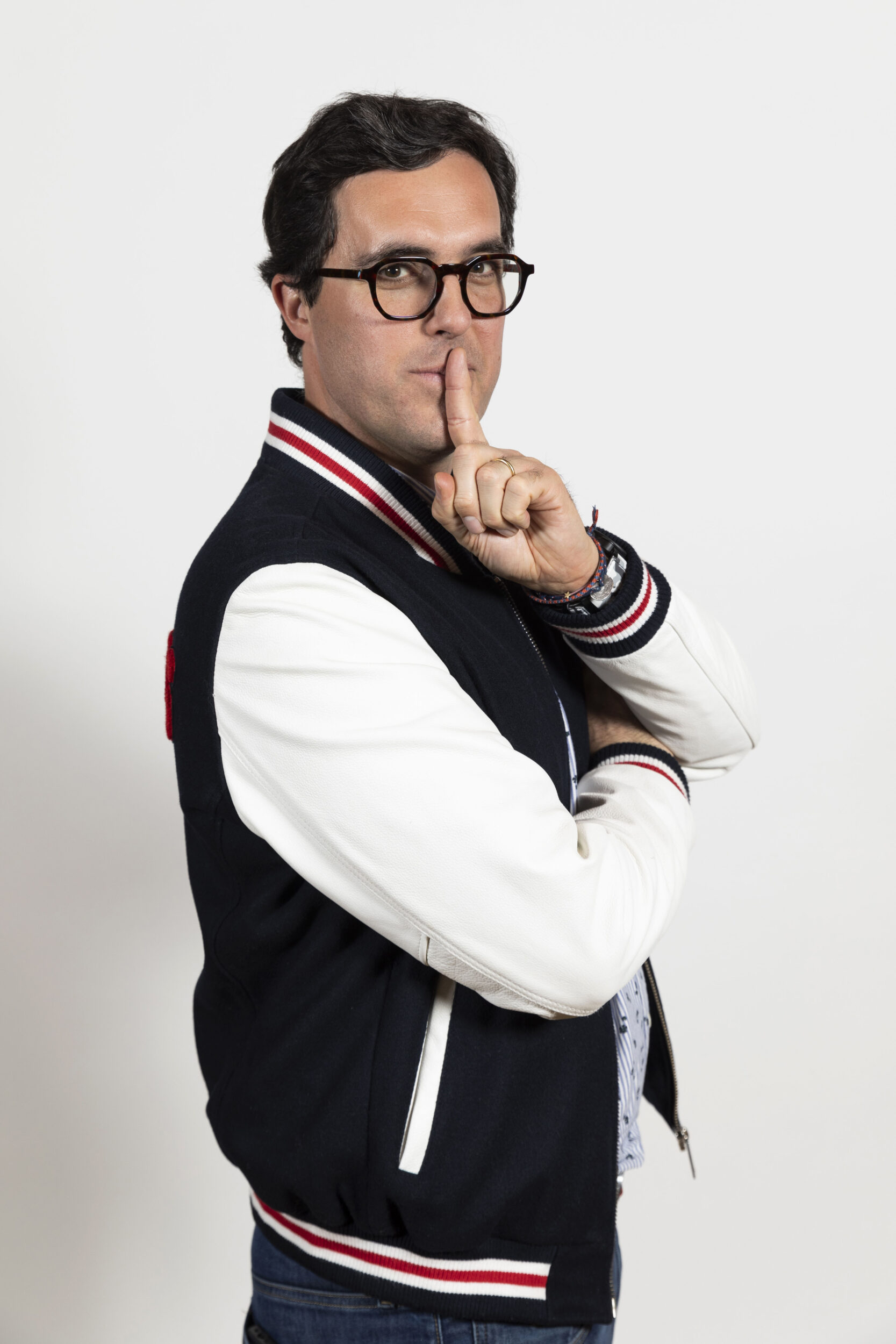 Photo de portrait en studio du mentaliste Burt Wayne, l'index de sa main gauche est devant sa bouche, il regarde dans l'objectif