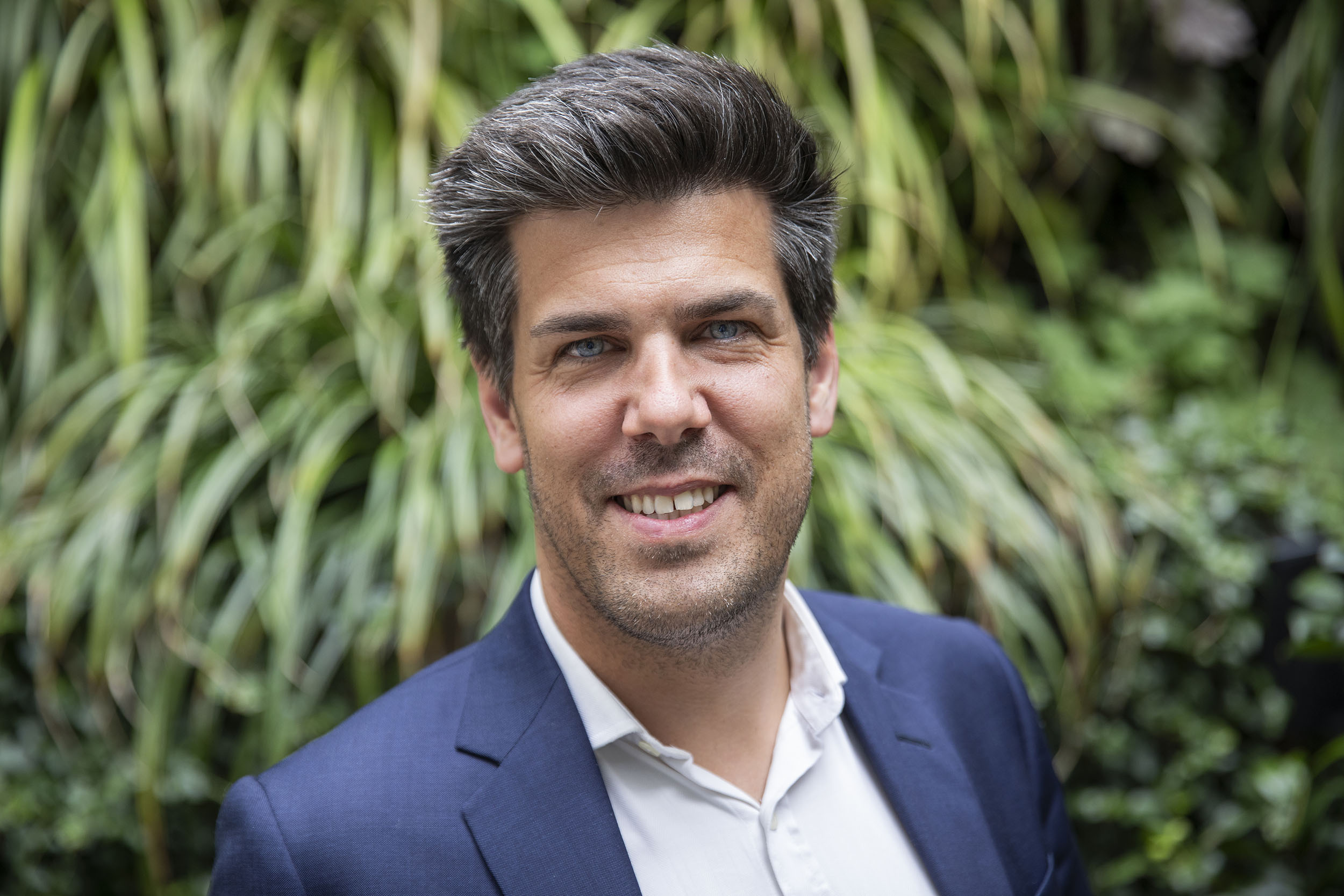 Photo de portrait corporate de M. Benjamin Verlingue, PDG du groupe Adelaïde, il est dans un jardin et regarde dans l'objectif