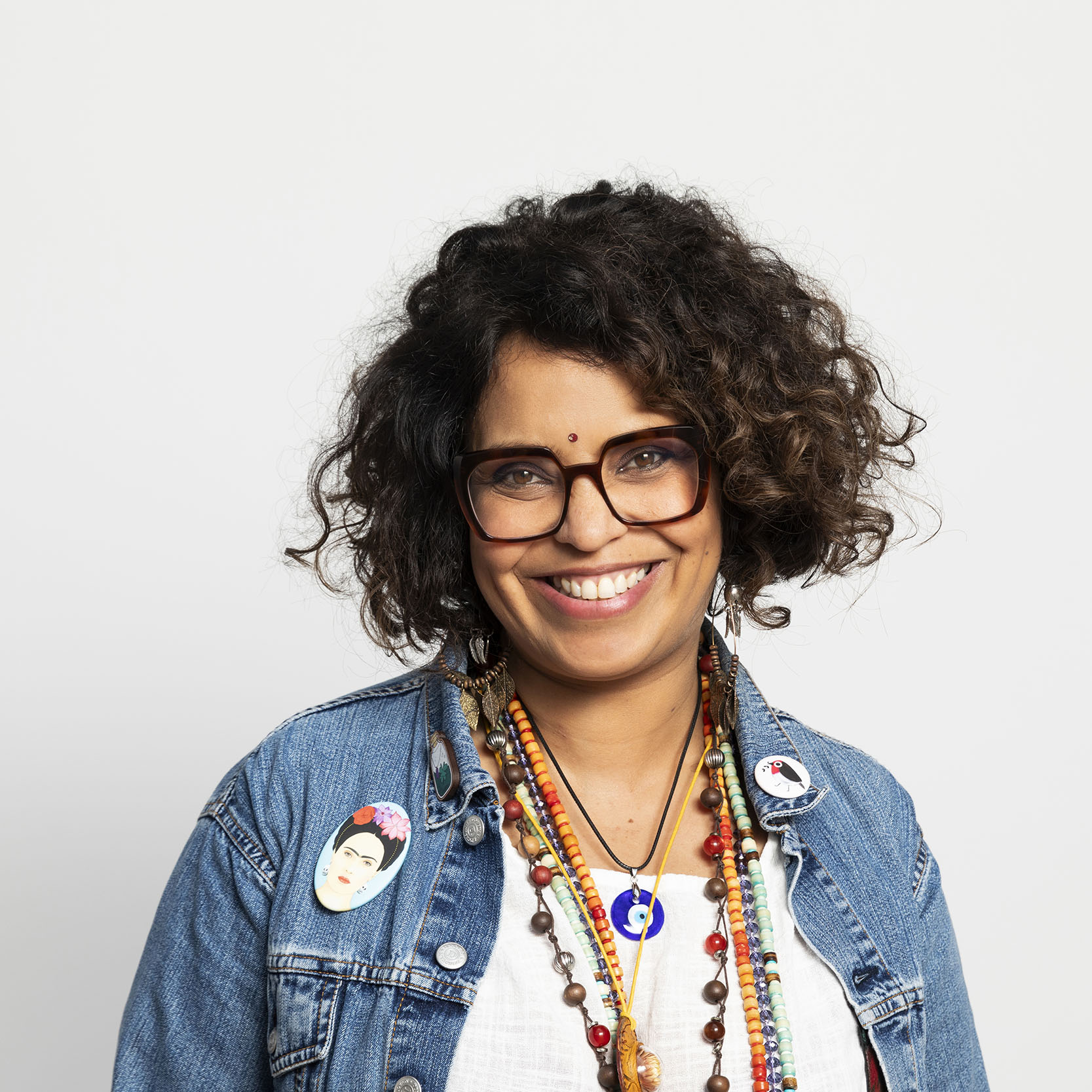 Photographie de portrait corporate d'une femme souriante aux cheveux bouclés portant des lunettes.